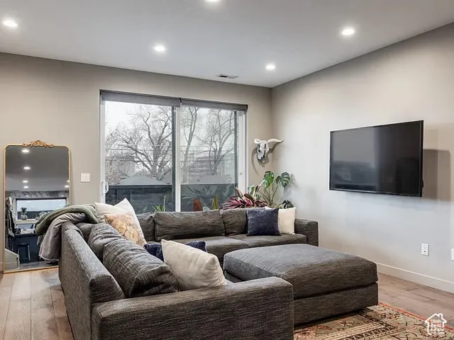 Recessed ceiling lighting, sliding glass door, neutral wall paint, wood-finish flooring, and white trim