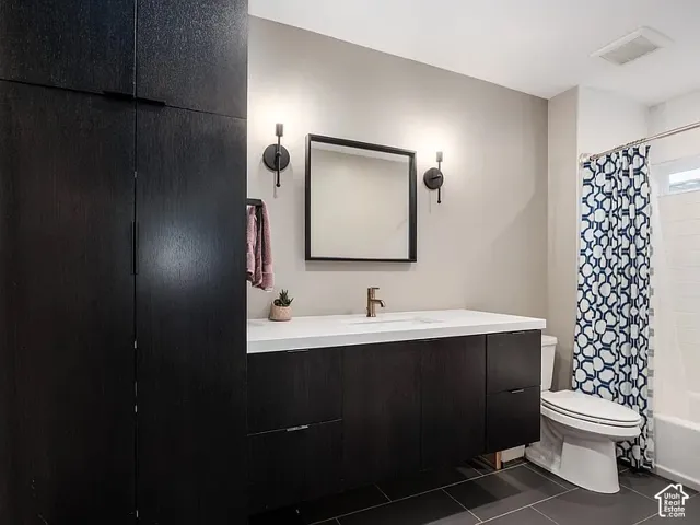 Floating vanity with a white countertop and integrated sink, bronze-finish faucet, dark wood-finish cabinetry, and a rectangular mirror with sconce lighting