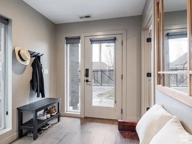 Wood-finish flooring, full-light entry door, sidelight window, and neutral wall tones
