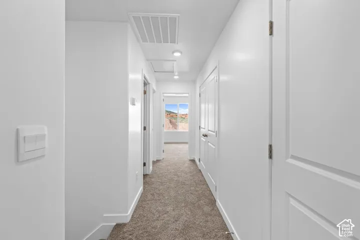 Bright hallway with recessed lighting, light-colored carpeting, and white paneled doors