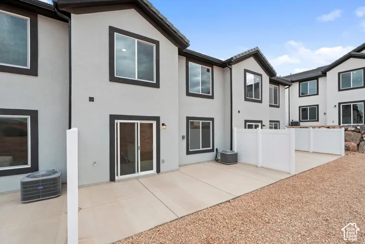 Rear exterior with a concrete patio, white privacy fencing, and a gravel landscape area
