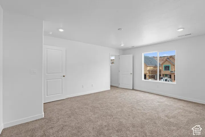 Recessed lighting illuminates the carpeted flooring and white interior walls