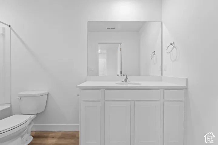 White vanity with shaker-style cabinetry, a built-in sink, and a rectangular mirror
