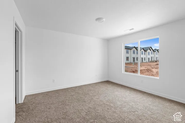 Neutral color palette, plush carpet flooring, recessed ceiling light, white trim, and a large window