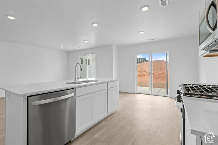 Kitchen featuring a stainless-steel gas range, matching overhead microwave, and a large island with an undermount sink and dishwasher