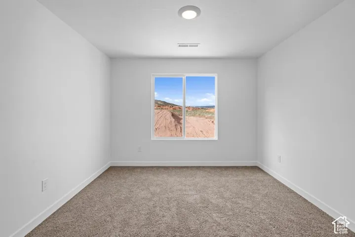Neutral wall finishes with a single window, recessed lighting, and carpeted flooring
