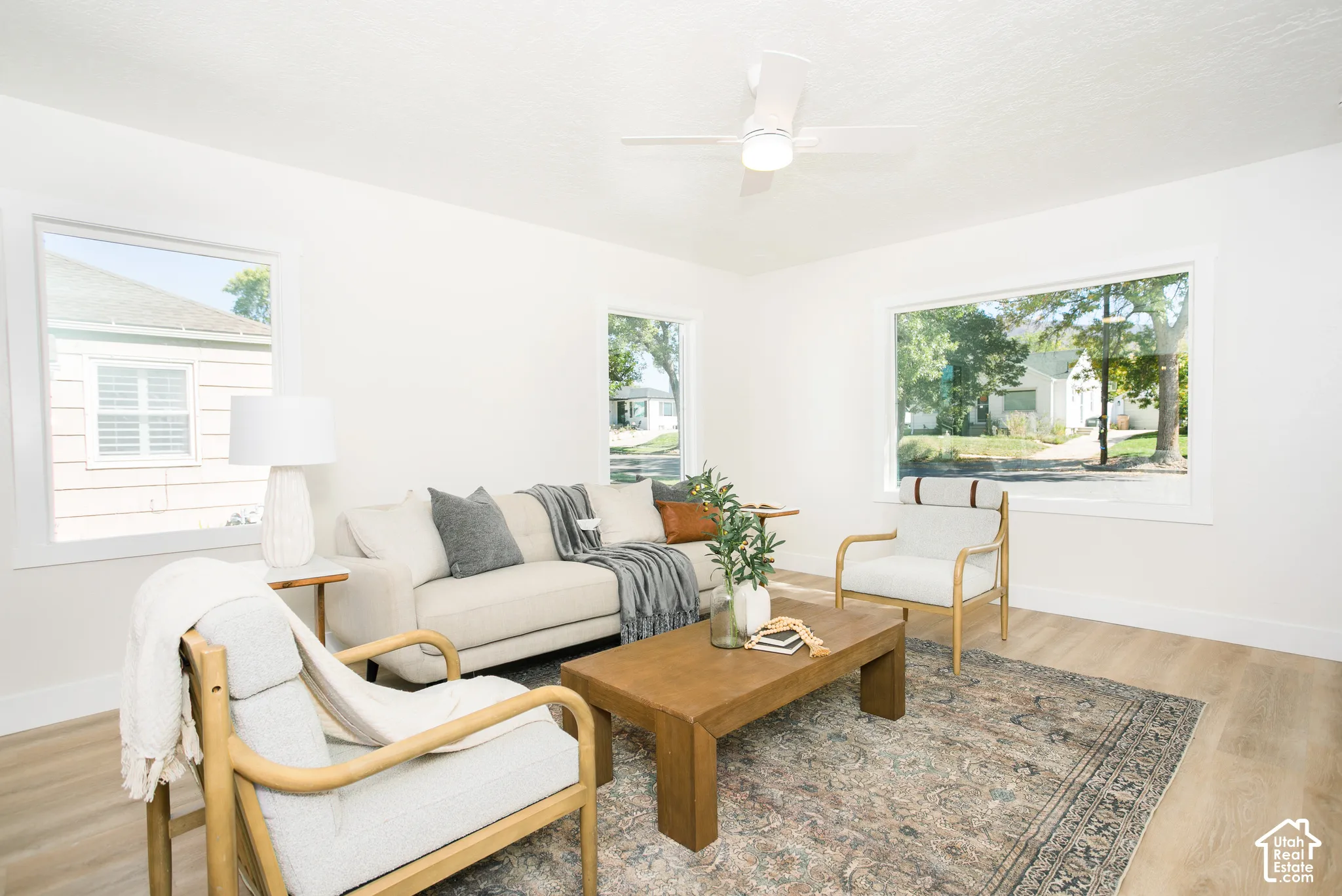 Bright living space with wood-finish flooring, white walls, and a ceiling fan