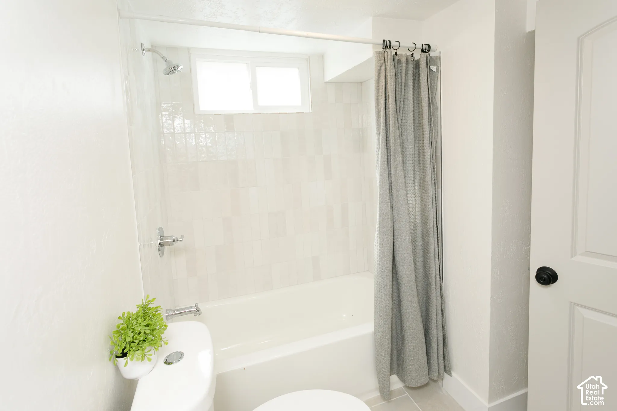 White subway tile shower surround with chrome fixtures, a built-in bathtub, and an integrated window