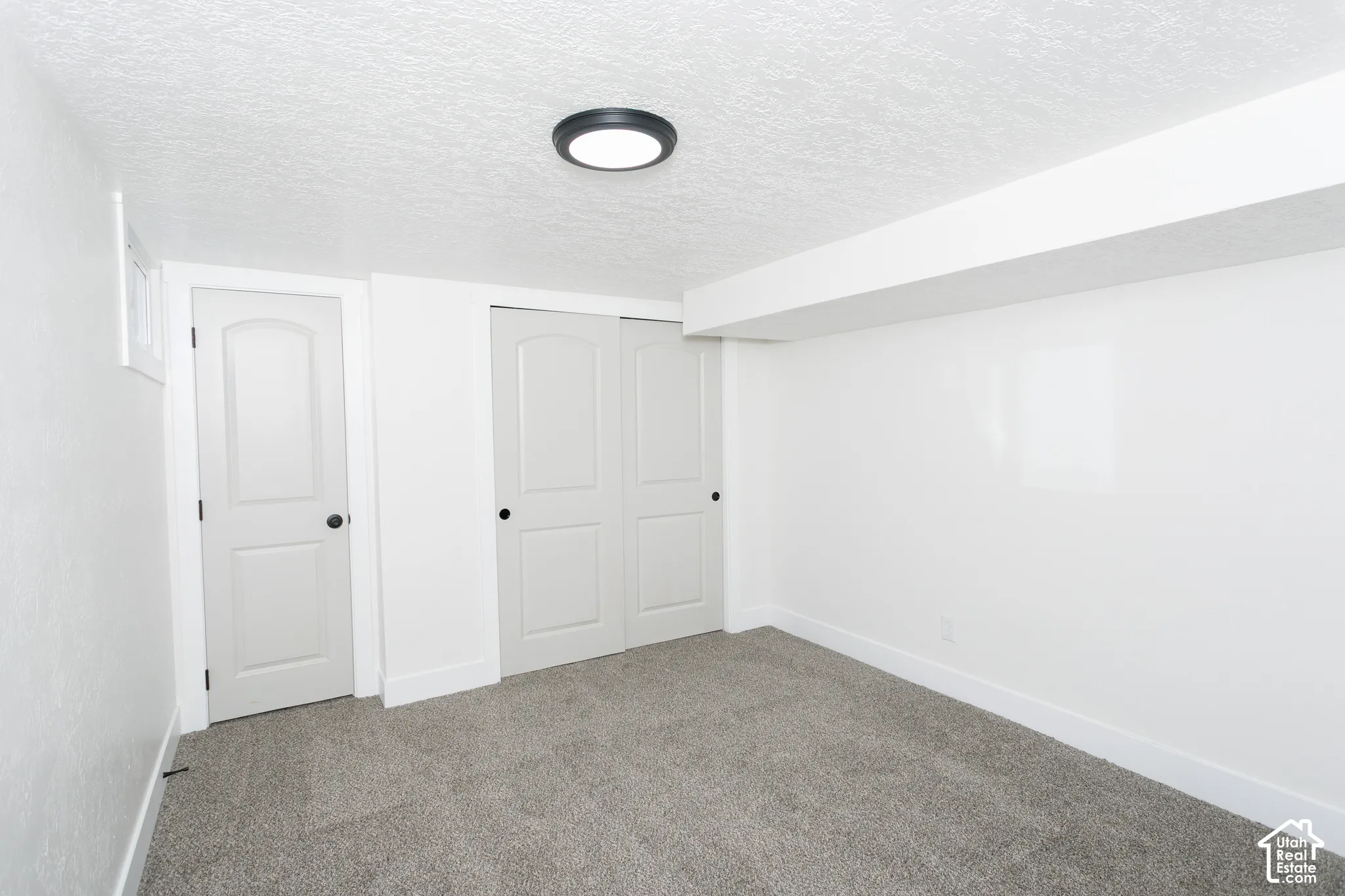 Neutral-toned carpet flooring, white walls, white trim, and a white ceiling with a flush-mount light fixture