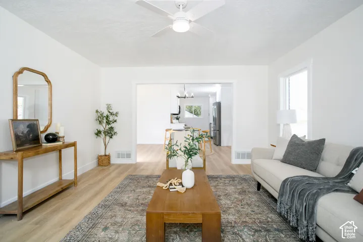 Wood-finish flooring throughout, white painted walls, ceiling fan, and recessed doorway