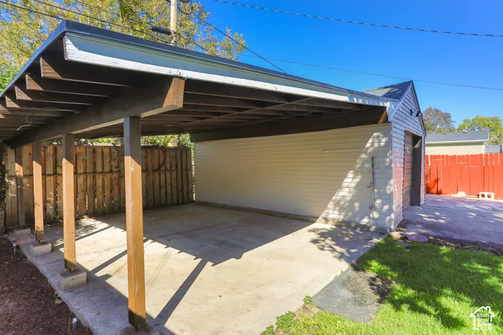 Covered carport, concrete paving, wood privacy fence, detached structure, gabled roof