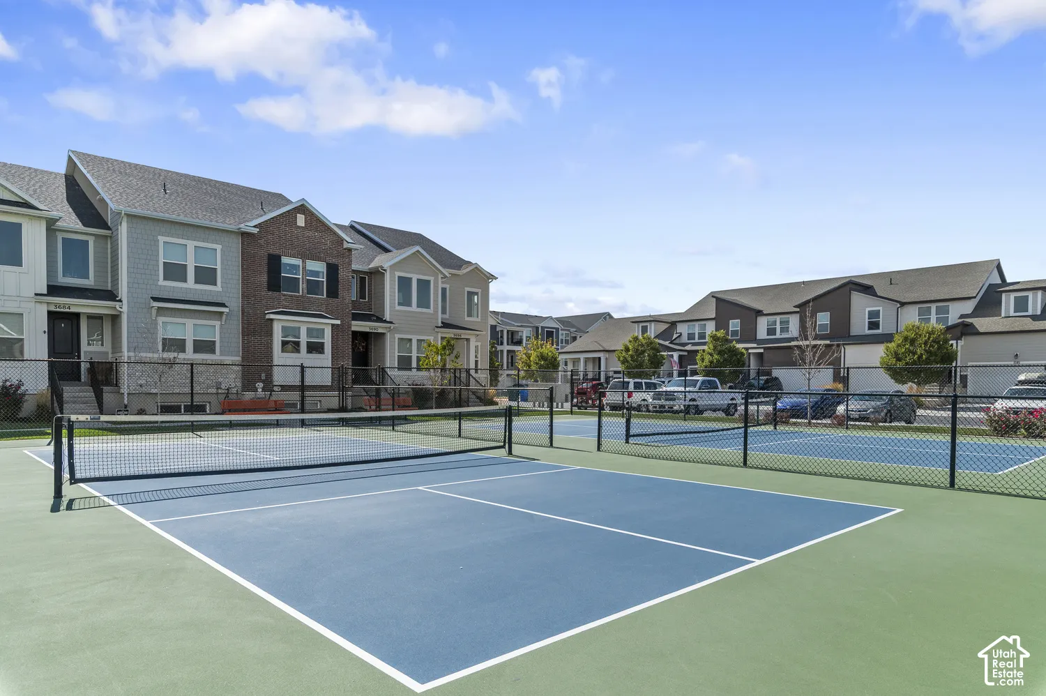 Community tennis and pickleball courts featuring hard court surfaces with professional-grade netting, white boundary lines, and ample lighting infrastructure