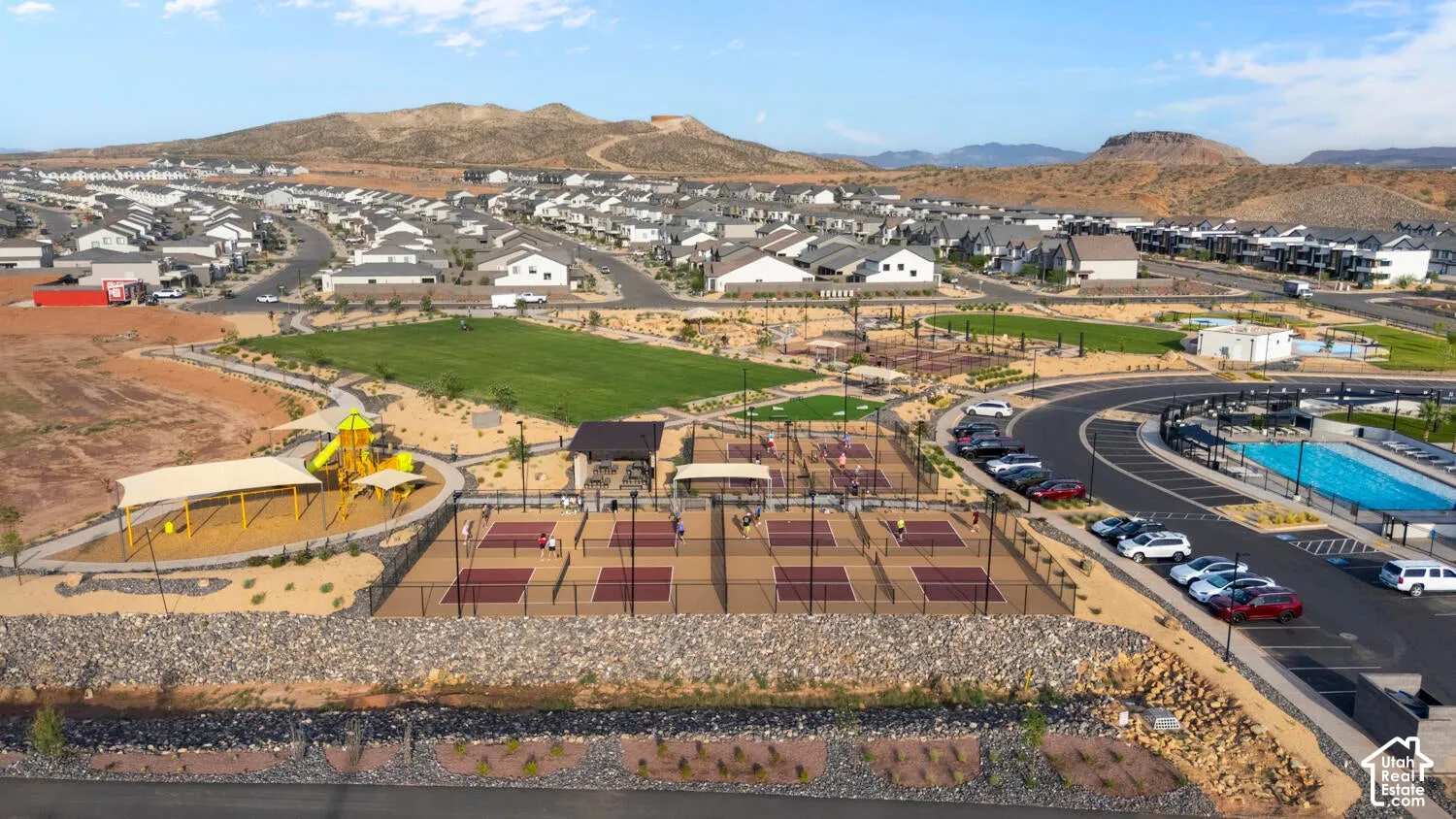 Community amenities featuring multiple pickleball courts, a playground with shade structures, a large green space, and a swimming pool
