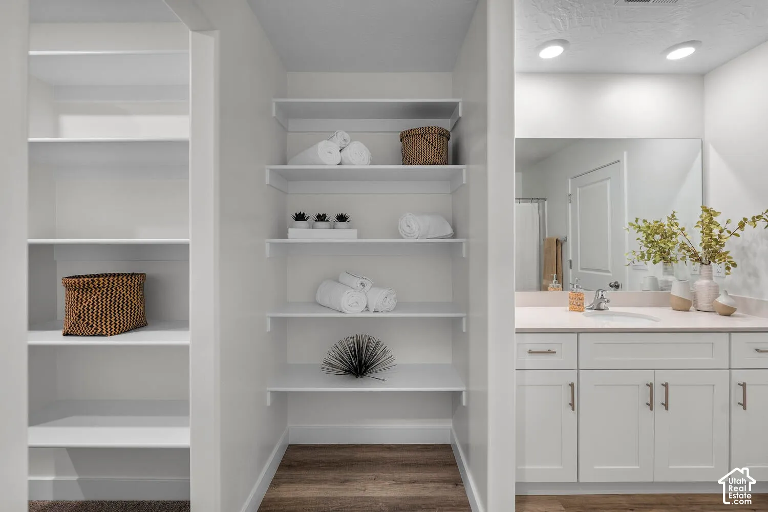 White cabinetry with modern hardware, integrated sink, and expansive mirror
