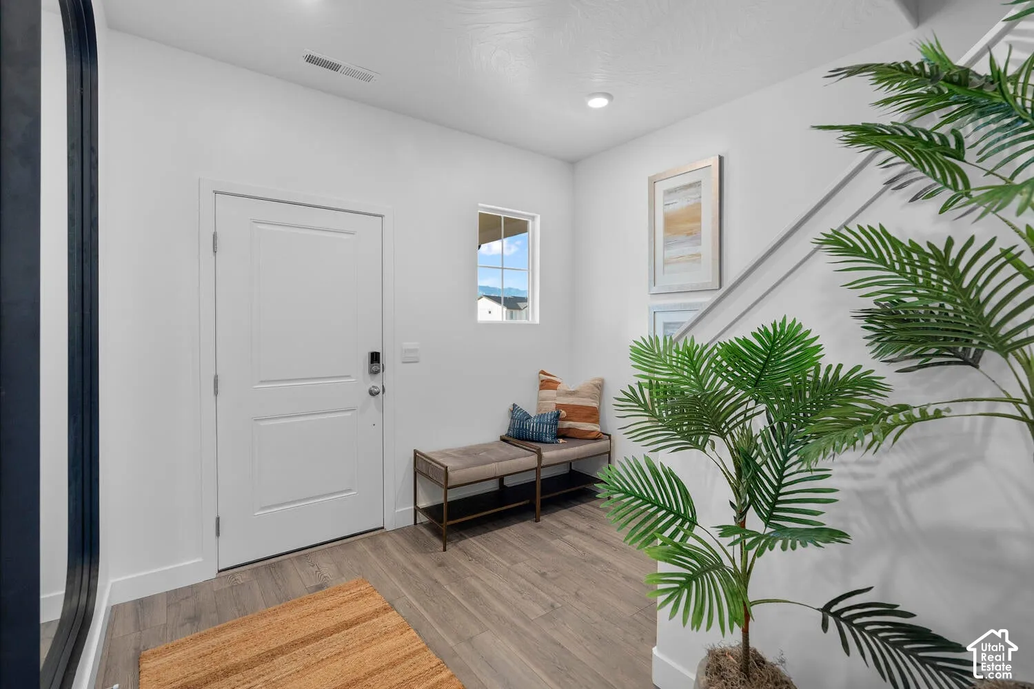 White entry door with smart lock, wood-finish flooring, recessed lighting, and a white framed window