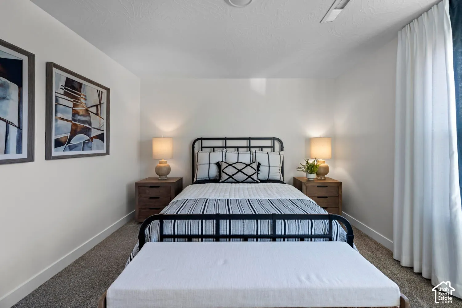 Carpeted flooring, white walls, built-in ceiling light, and window with white drapery