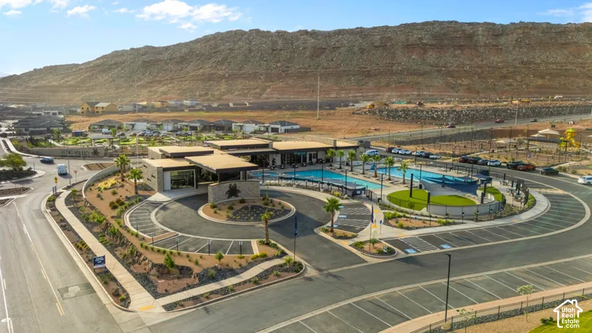 Community clubhouse with multiple swimming pools, circular drive, and lush desert landscaping