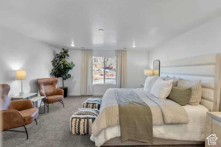 Carpeted flooring, recessed lighting, and a single window with vertical blinds