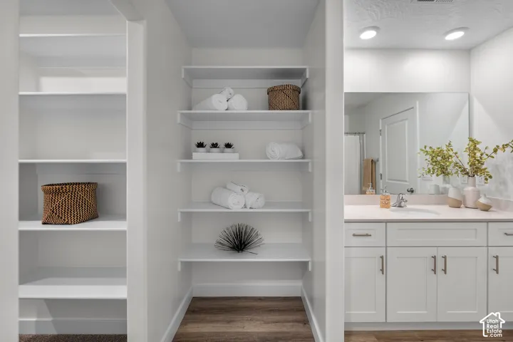 White cabinetry with modern hardware, integrated sink, and expansive mirror