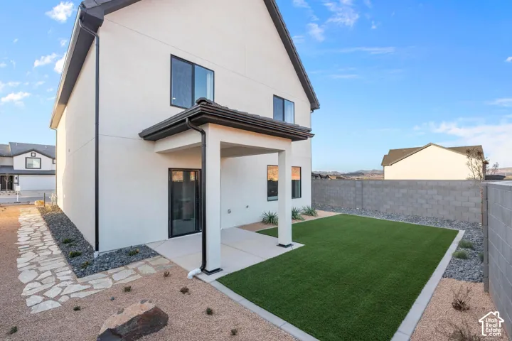 Exterior featuring a covered patio, artificial turf, low-maintenance landscaping, and a privacy wall