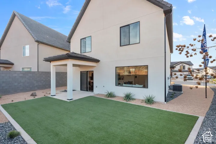 Private backyard featuring artificial turf, a covered patio, and gravel landscaping
