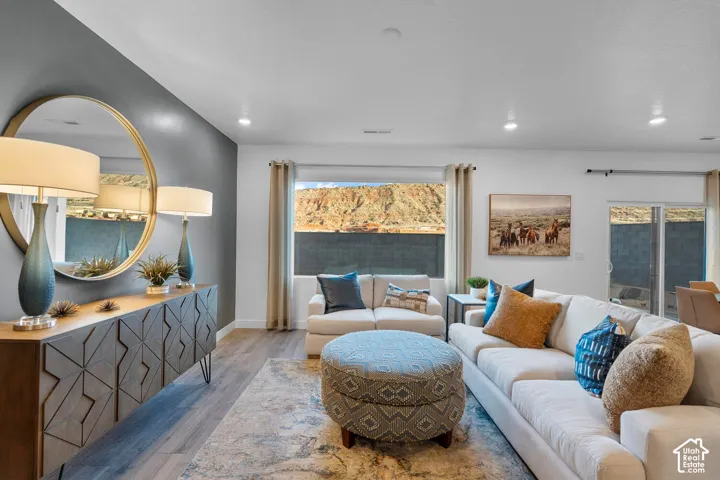 Recessed lighting illuminates the open-concept living space, featuring wood-finish flooring and a sliding glass door