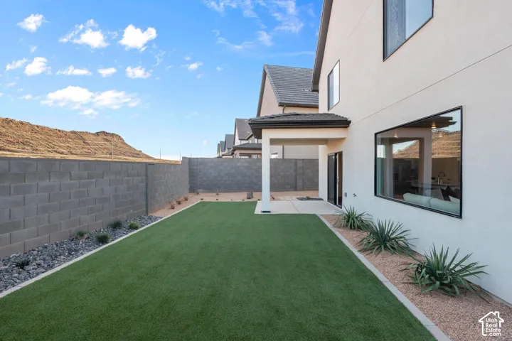 Expansive backyard featuring artificial turf, a covered patio, and desert landscaping