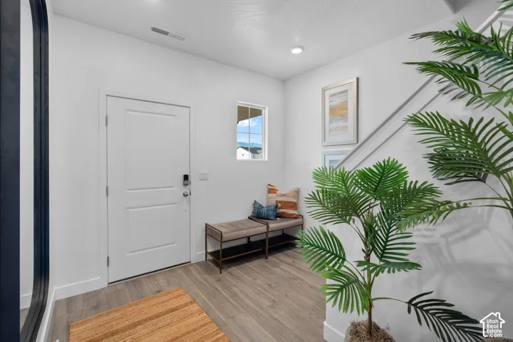 White entry door with smart lock, wood-finish flooring, recessed lighting, and a white framed window