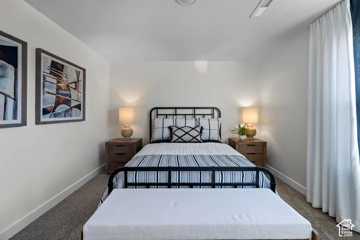 Carpeted flooring, white walls, built-in ceiling light, and window with white drapery