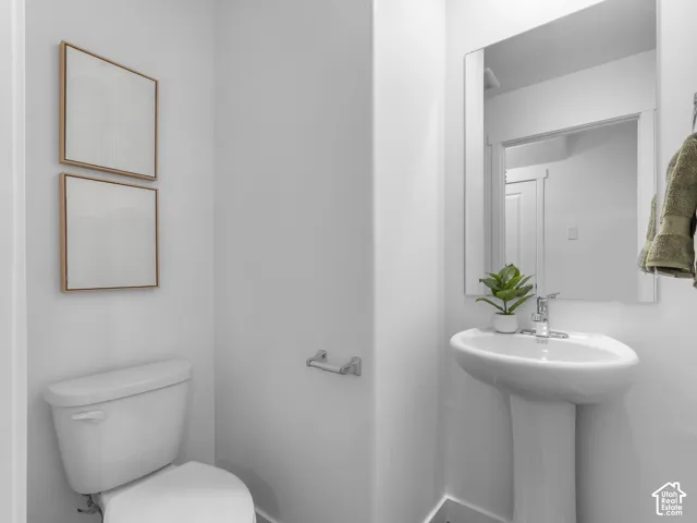 White pedestal sink with a chrome faucet, adjacent to a white toilet