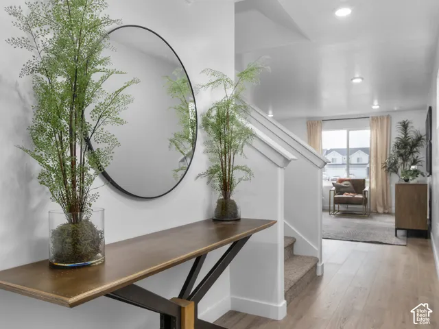 Recessed lighting, wood-finish flooring, white walls, and a staircase with white risers and carpeted treads