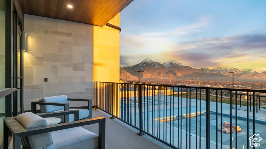 Balcony featuring a wood-panel ceiling, stone wall cladding, and dark metal railings