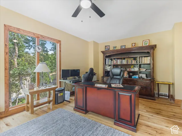 Hardwood flooring, expansive window with natural wood trim, built-in ceiling fan, built-in cabinetry