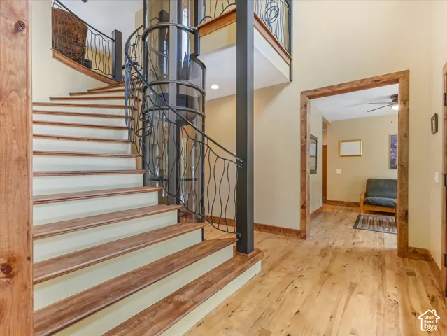 Spiral staircase with wood-finish treads, decorative metal railing, and an integrated cylindrical elevator