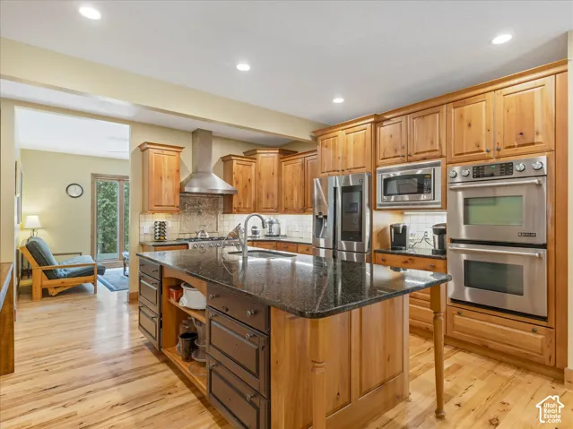 Kitchen featuring wood cabinetry, stainless steel appliances, a center island with a dark countertop, and recessed lighting