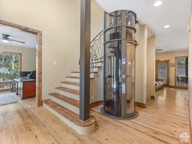 Open-concept living space featuring wood-finish flooring, a spiral staircase with an ornate iron railing, and a built-in cylindrical elevator