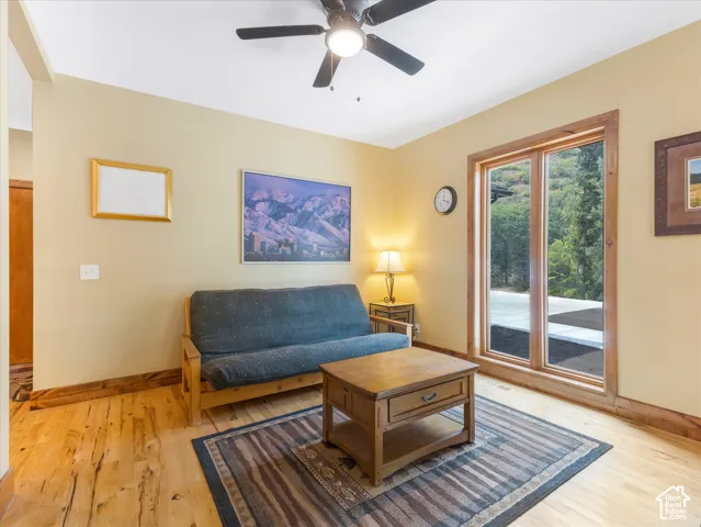 Light wood-finish flooring with coordinating wood trim, a ceiling fan, and large sliding glass doors