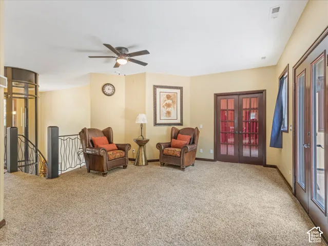 Open loft area featuring an elevator, wrought iron railing, and a ceiling fan