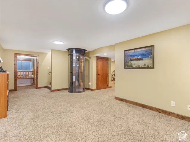 Carpeted room featuring a built-in cylindrical elevator, recessed lighting, wood trim, and a wood-framed doorway