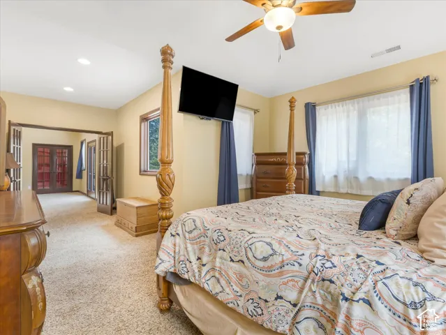 Recessed lighting, ceiling fan, carpet flooring, windows with natural wood trim, and French doors