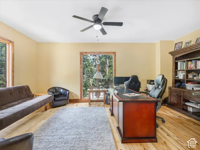 Wood-finish flooring with a ceiling fan and recessed lighting