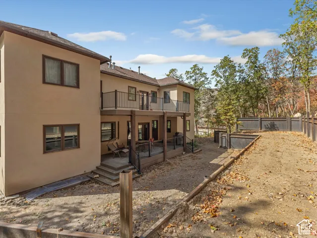 Stucco exterior featuring a multi-level deck with metal railings and a fenced perimeter