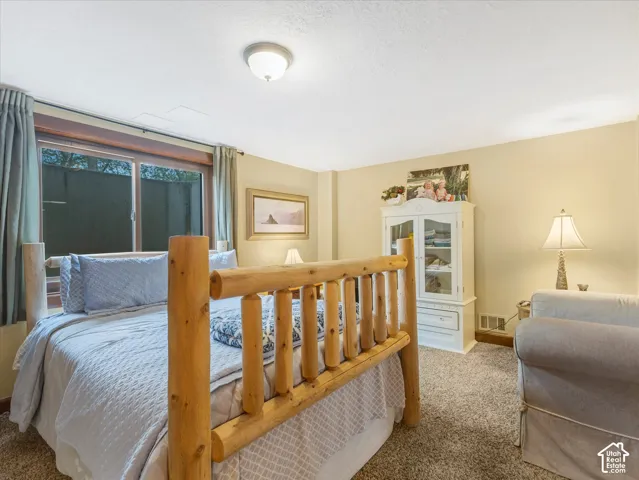 Wood-finish log bed frame, wall-to-wall carpeting, built-in shelving unit, and a ceiling-mounted light fixture
