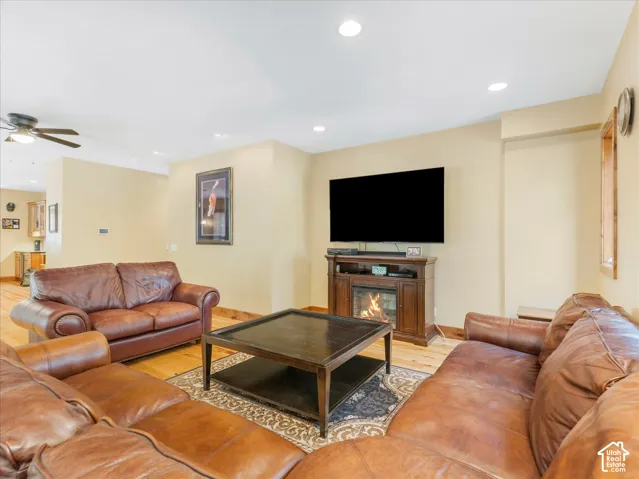 Recessed lighting, wood-finish flooring, wood-paneled accents, and a built-in media console with an electric fireplace