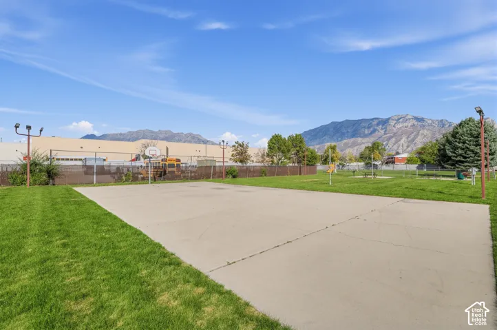 Expansive recreational area featuring a concrete court surface, chain-link fencing, and mature landscaping with lush green lawn