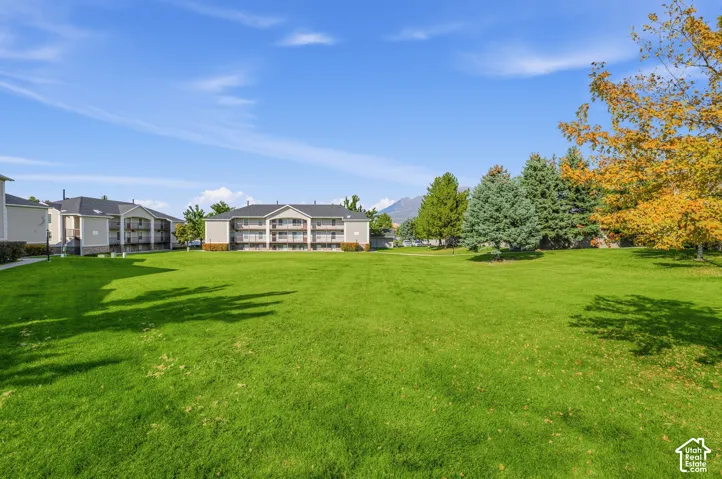 Expansive green lawn with mature trees and visible mountain backdrop