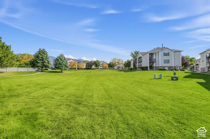 Expansive manicured lawn with mature landscaping and tree-lined perimeter