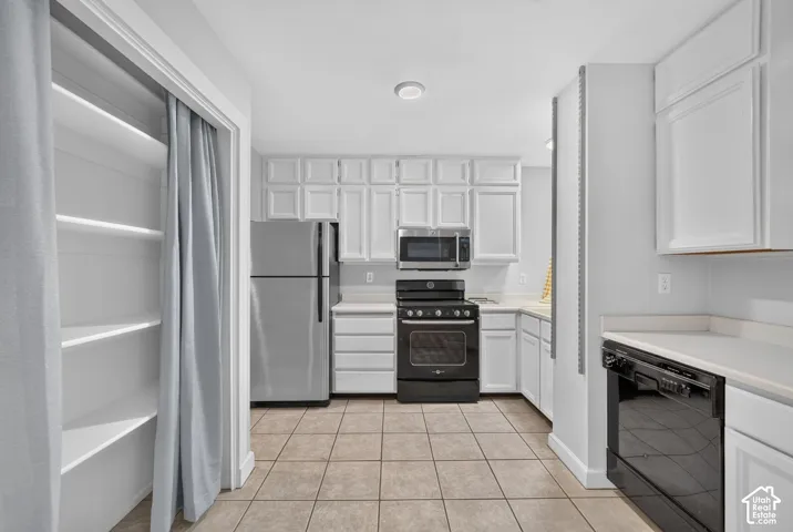 Kitchen featuring white cabinetry, light-toned countertops, and stainless steel appliances