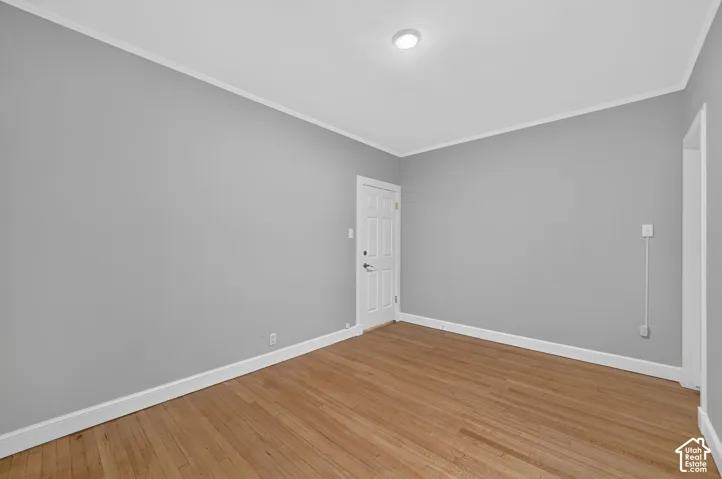 Hardwood flooring, crown molding, white trim, recessed lighting, and a paneled door