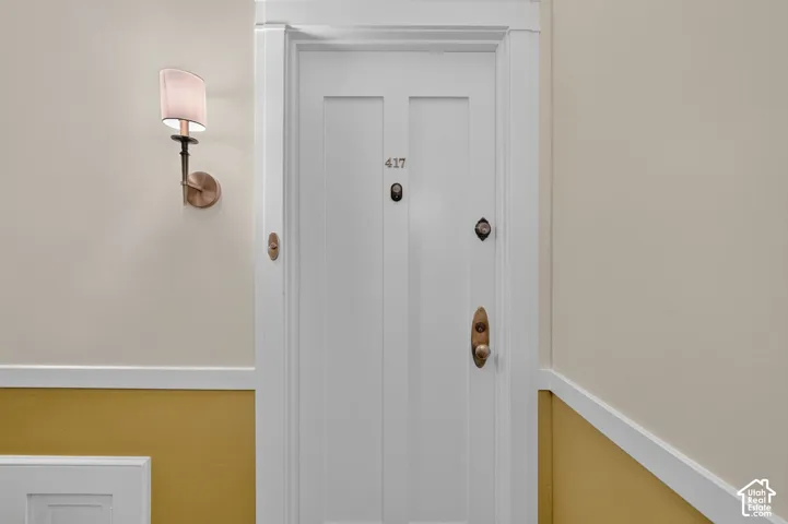 Hallway featuring classic white six-panel doors with oil-rubbed bronze hardware, neutral walls with crisp white trim, and two-tone paint detailing in warm gold and cream tones